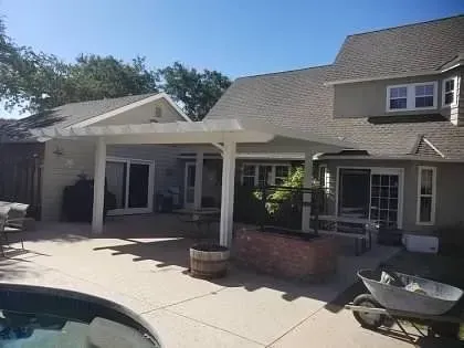 A house with a patio and a pool in front of it.