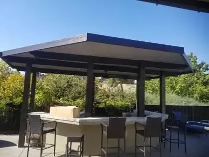 A large outdoor pavilion with a table and chairs underneath it.