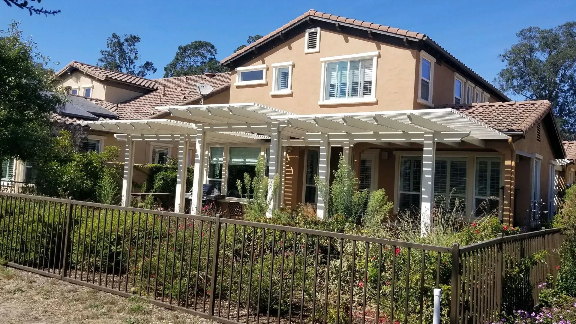 A large house with a pergola and a fence around it