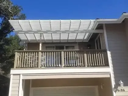 A house with a balcony and a pergola on top of it.