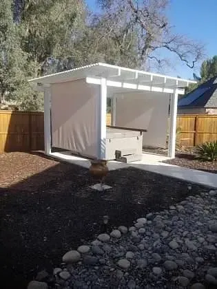 There is a gazebo in the backyard with a hot tub underneath it.