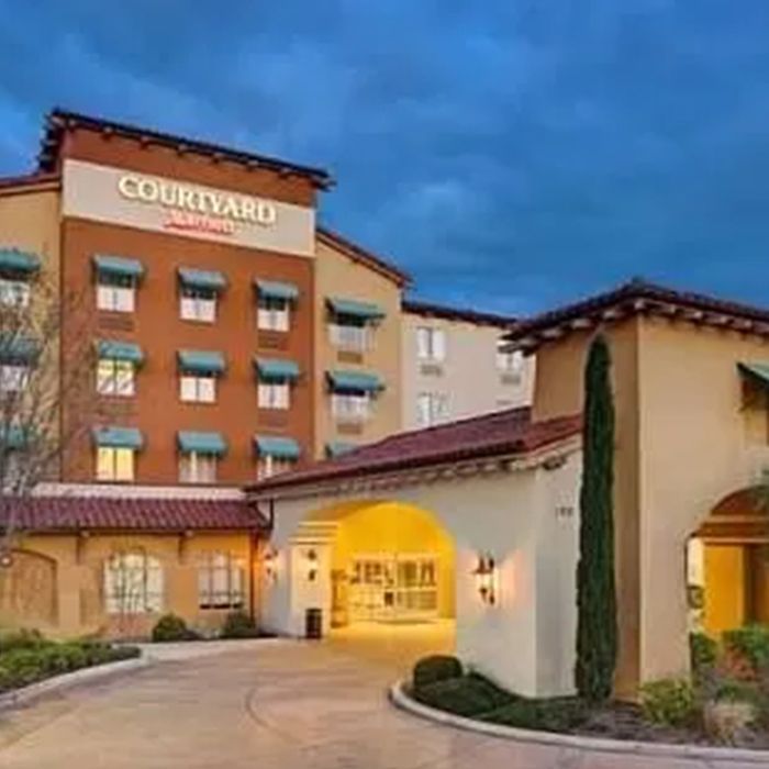 A large hotel with a lot of windows and a driveway leading to it. A large hotel with a lot of windows and a driveway leading to it.