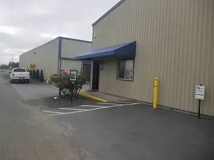 A white truck is parked in front of a building with a blue awning.