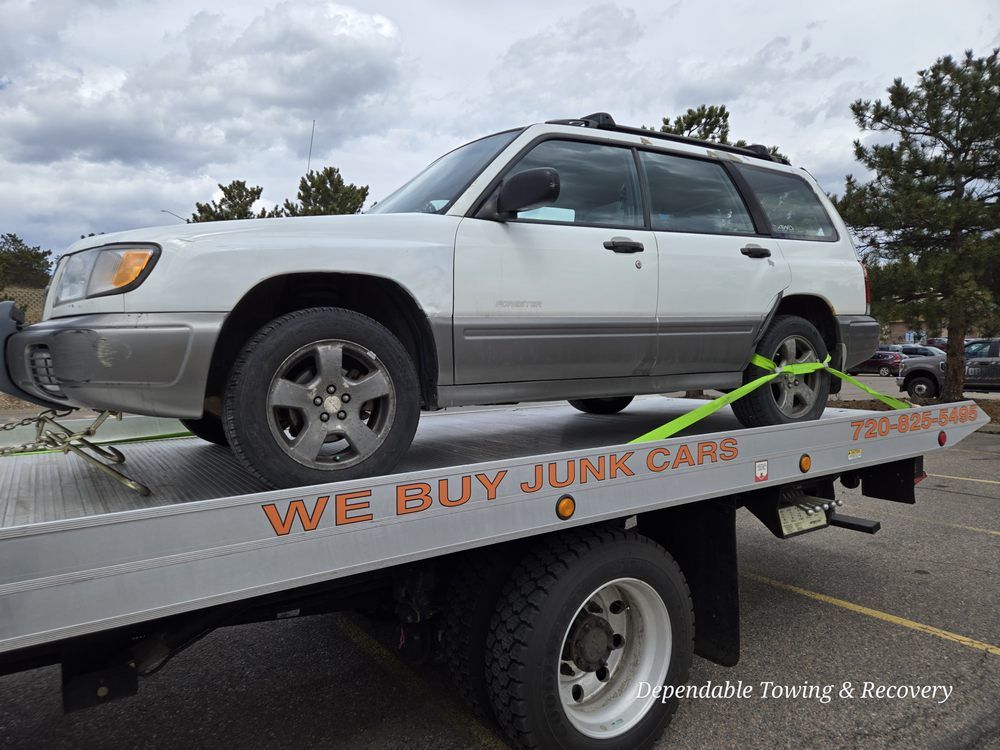 A white Subaru Forester loaded on a flatbed tow truck with the text 