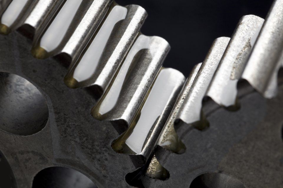 Primo piano di ingranaggi metallici che si ingranano, con un design leggermente curvo e superfici riflettenti.