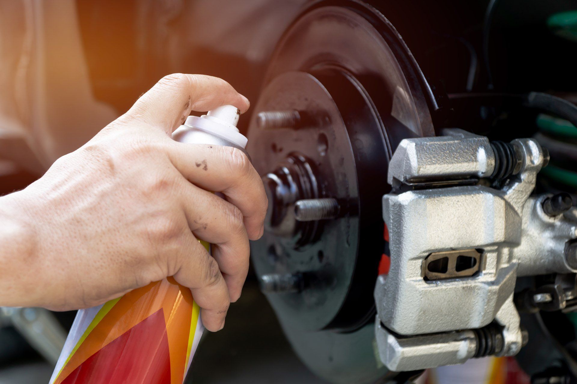 Spruzzatura manuale di detergente per freni sul gruppo freni di un'auto.