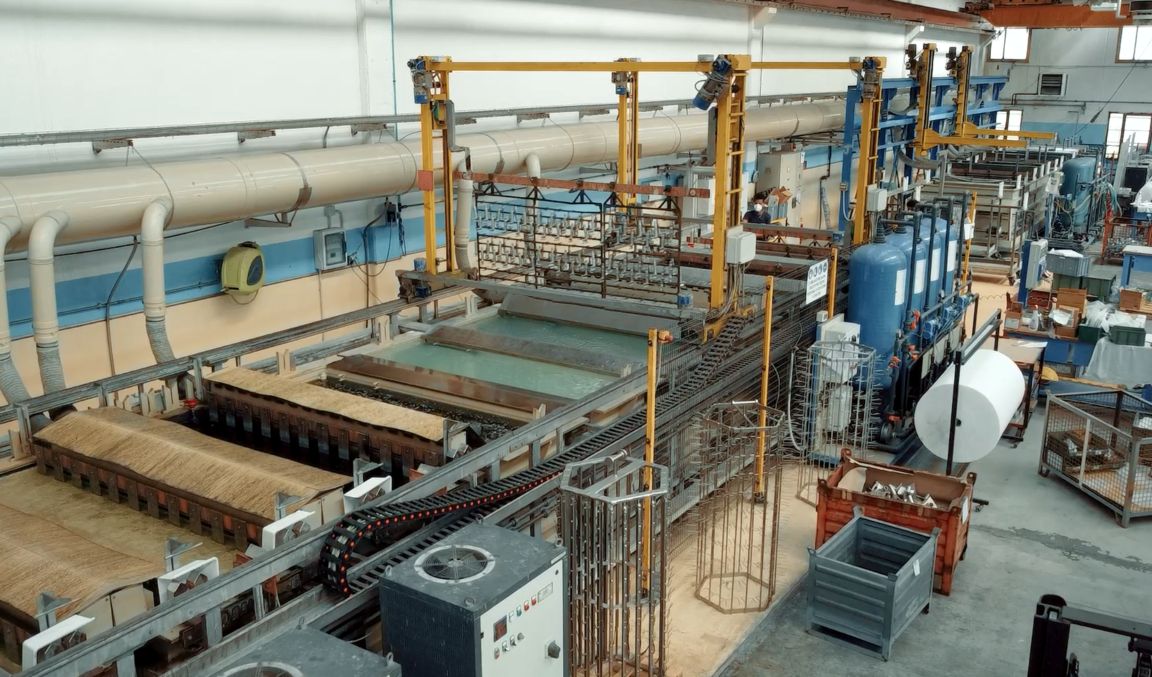 Linea di placcatura industriale con vasche, gru a ponte e attrezzature in ambiente di fabbrica.