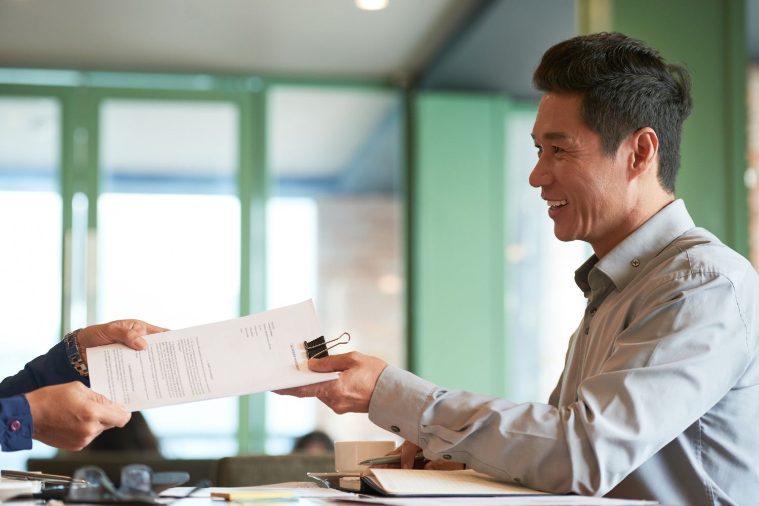 A man is handing a piece of paper to another man.