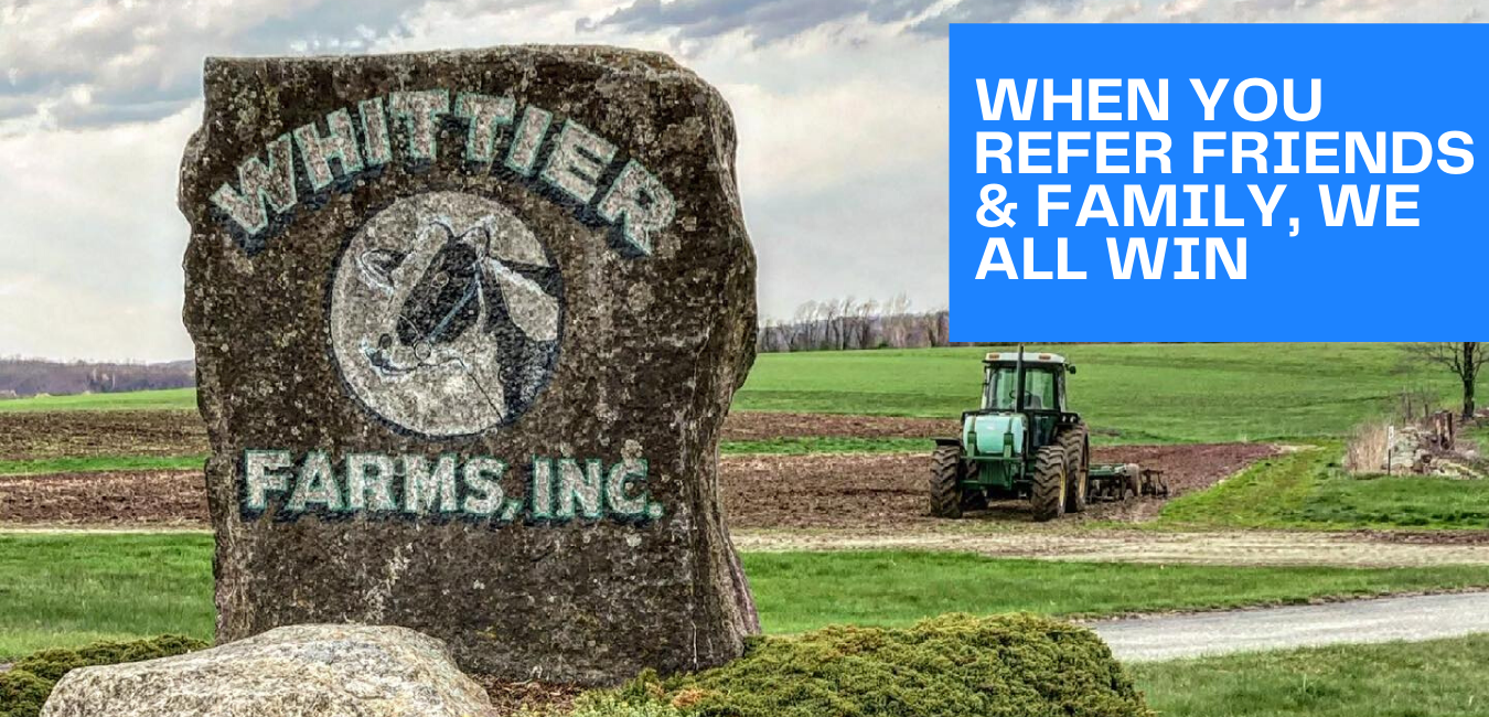 A sign for whittier farms inc. with a tractor in the background