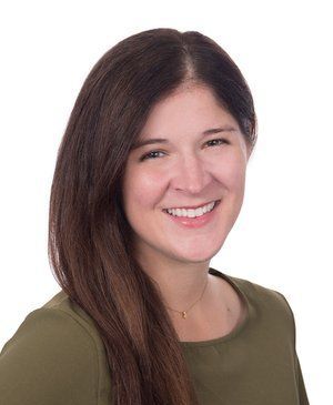 A woman with long brown hair is smiling and wearing a green shirt.