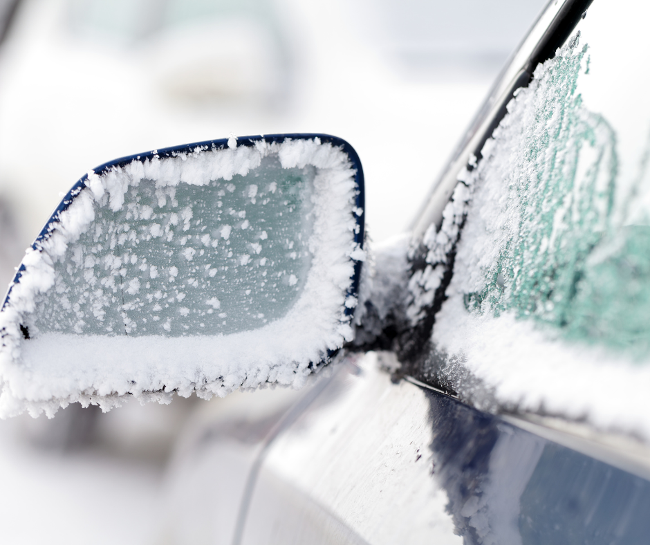 The rear view mirror of a car is covered in snow