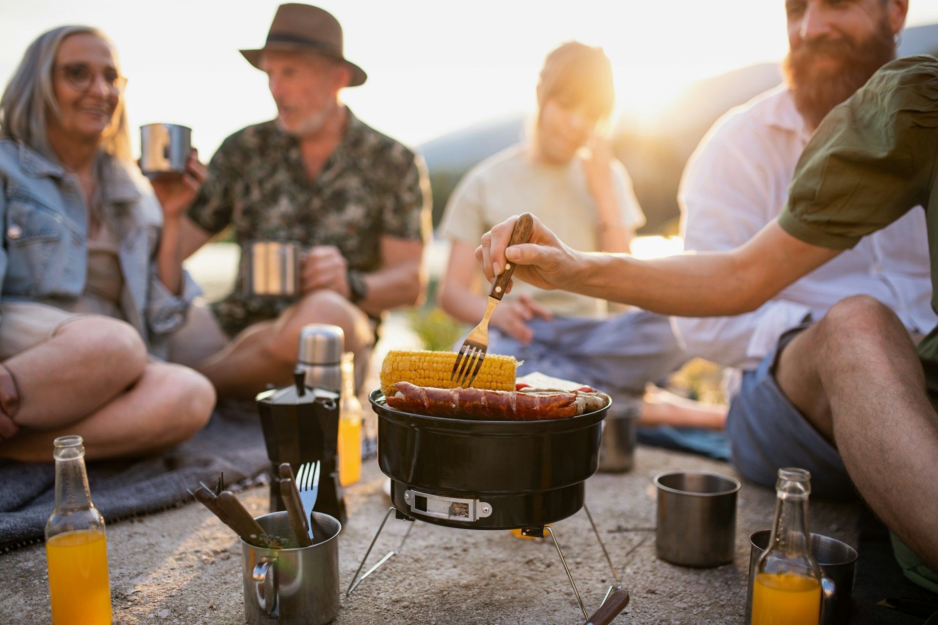 A group of people are sitting around a barbecue grill.