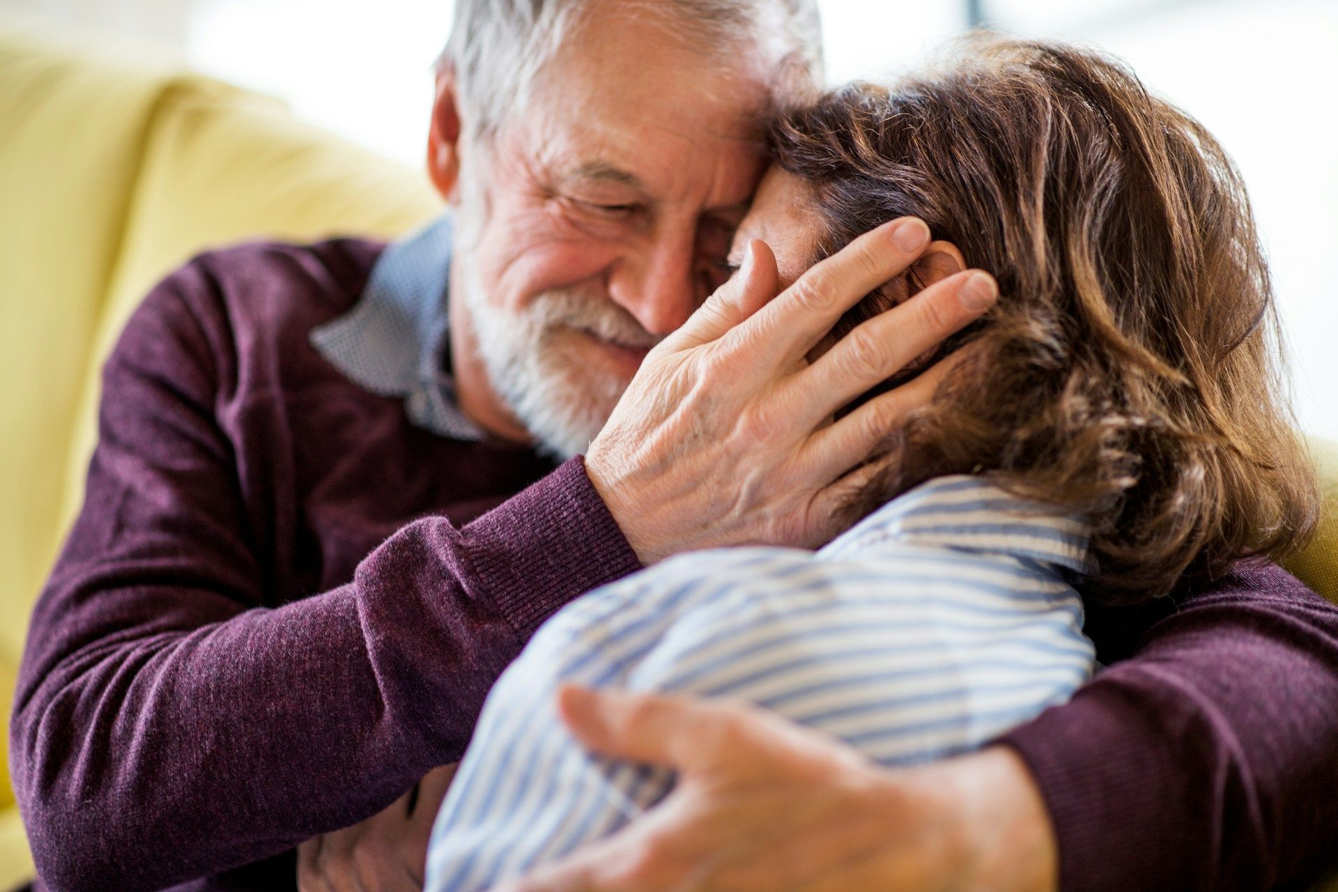 A man and a woman are hugging each other on a couch.