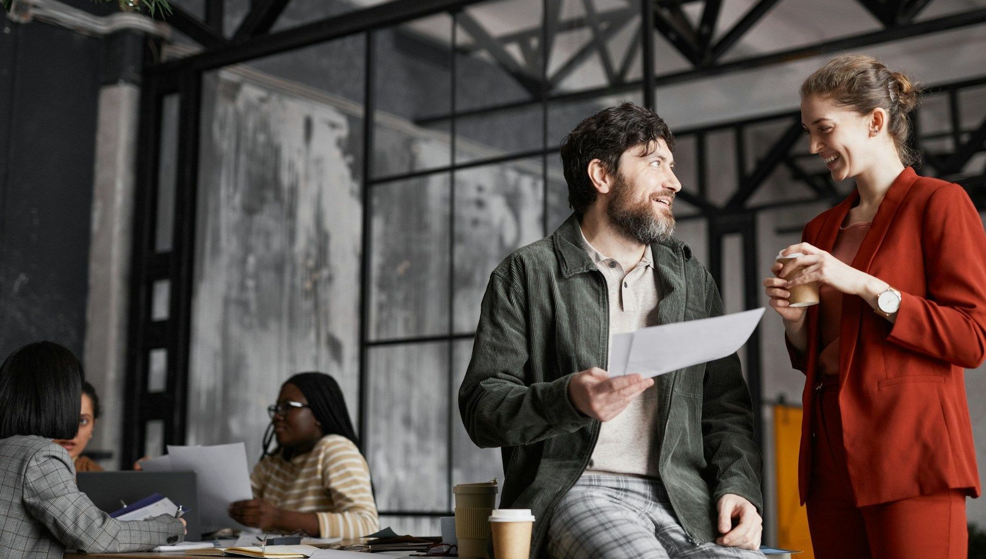 A man is holding a piece of paper while talking to a woman in an office.