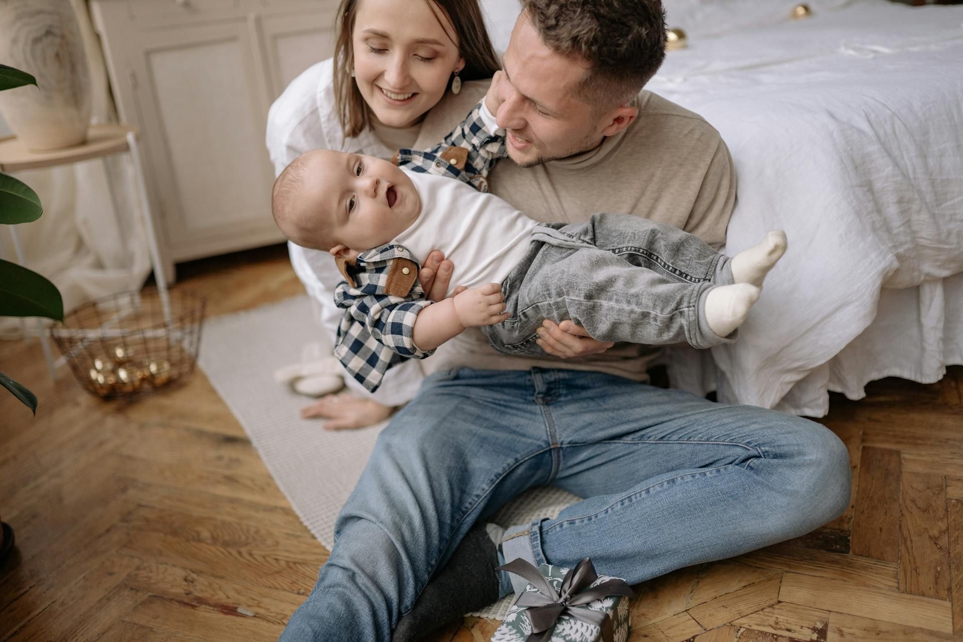 A man and woman are sitting on the floor holding a baby.