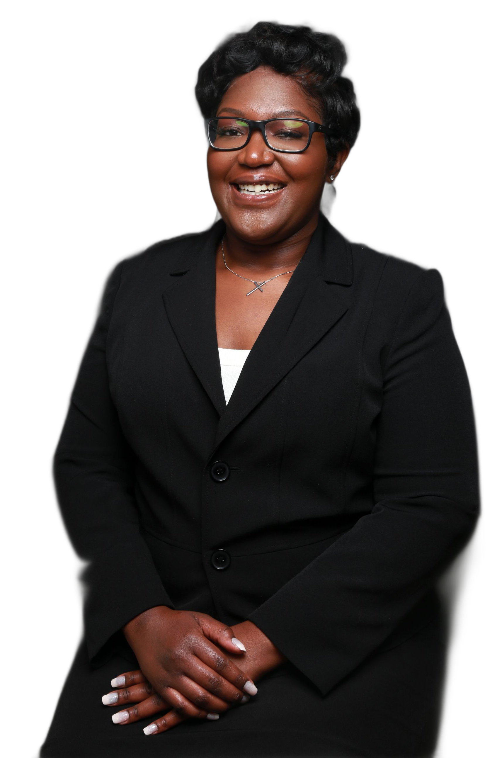 Woman in black suit, glasses, smiling, hands clasped.