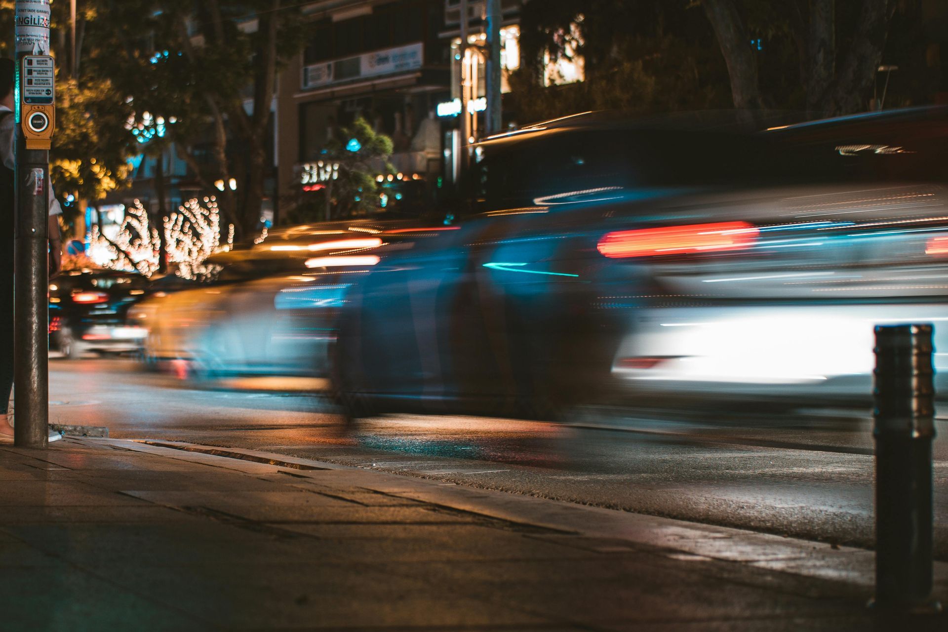 Cars speeding on a city street at night, with blurred headlights and taillights.