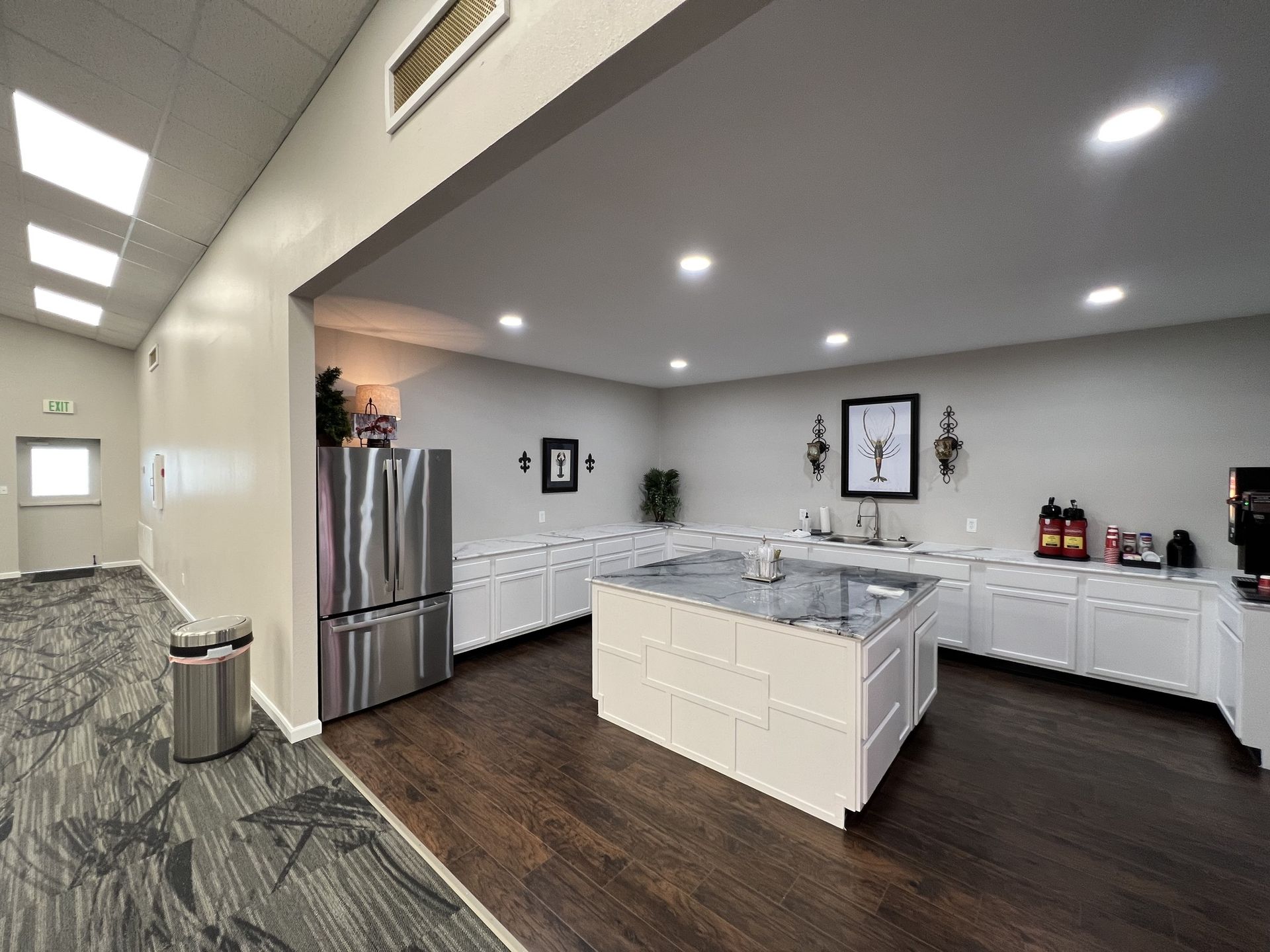 Modern kitchen with white cabinets, stainless fridge, island, and dark wood floors