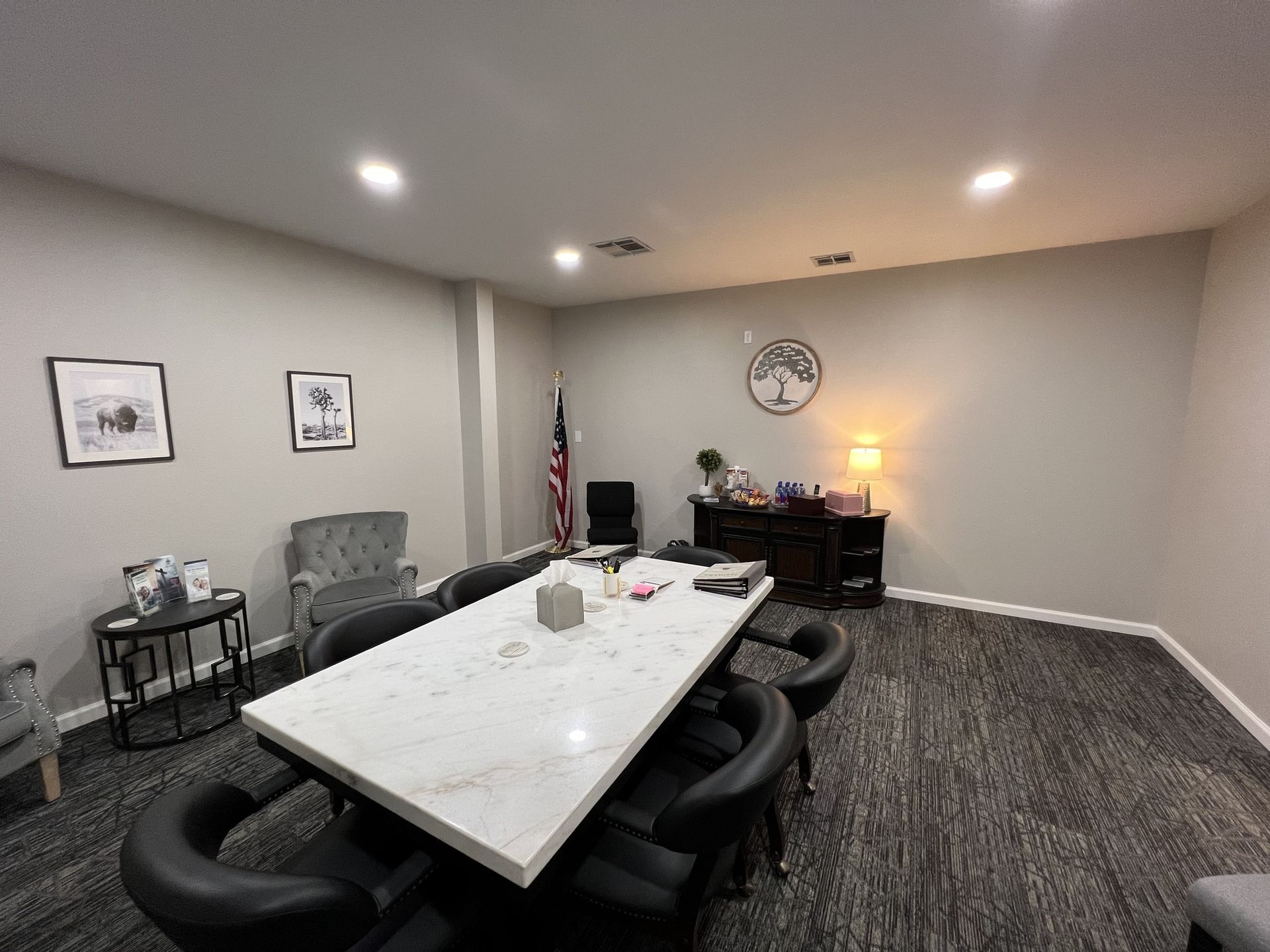 Conference room with marble table, black chairs, wall art, lamp, and an American flag.