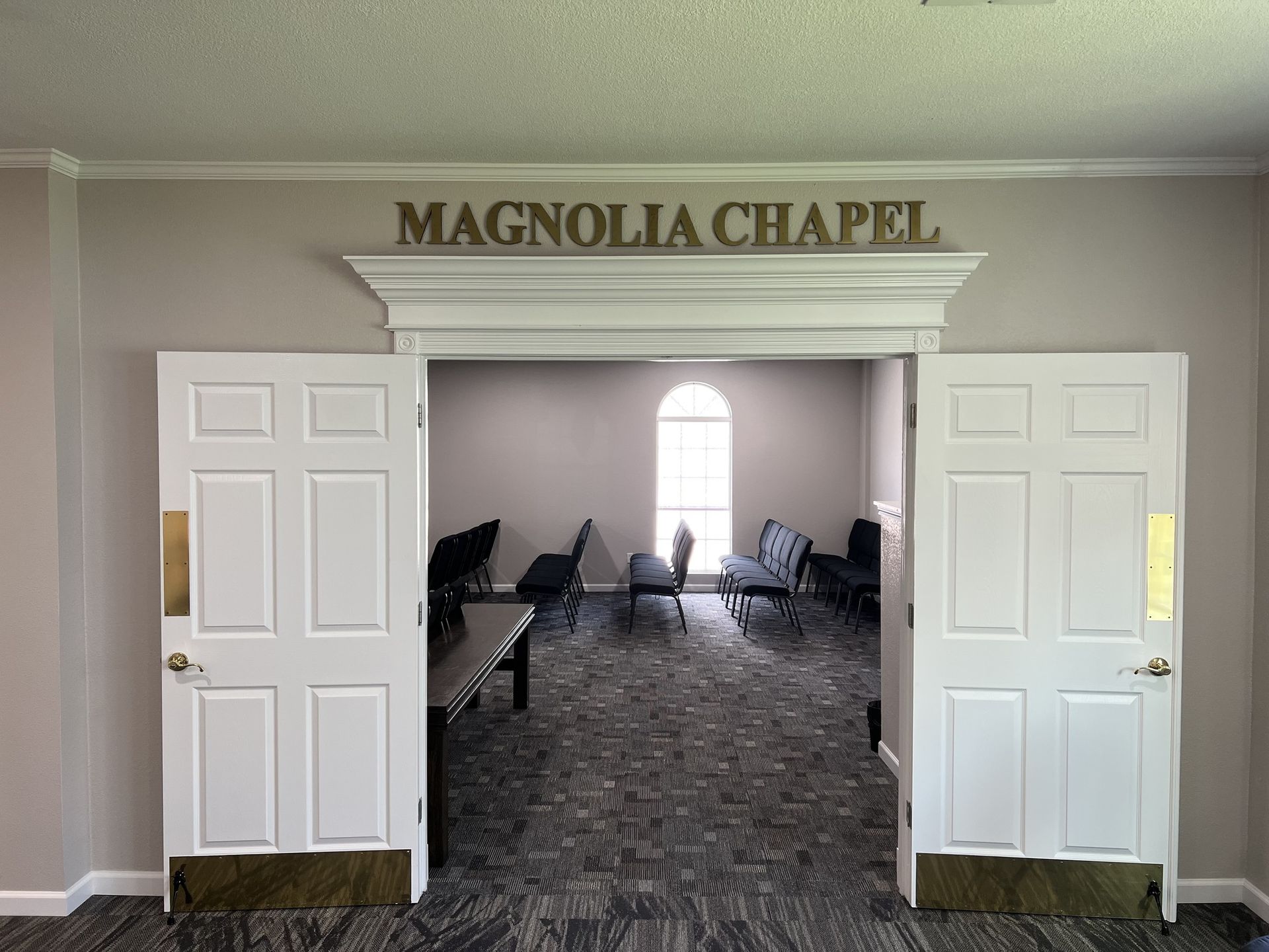 Magnolia Chapel entrance with open white double doors and rows of chairs inside
