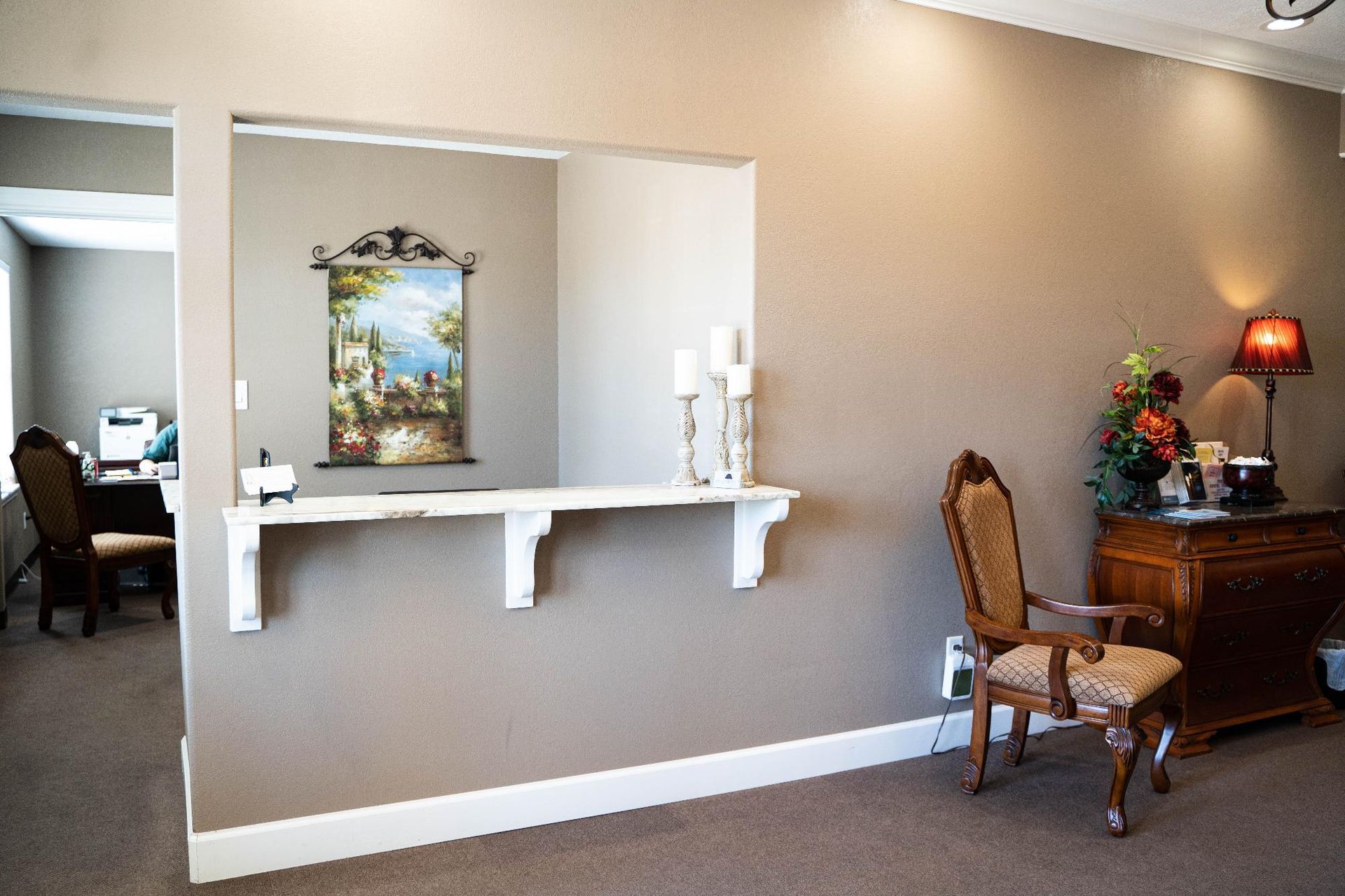 Modern lobby with a reception nook, chair, side table, lamp, and wall art.