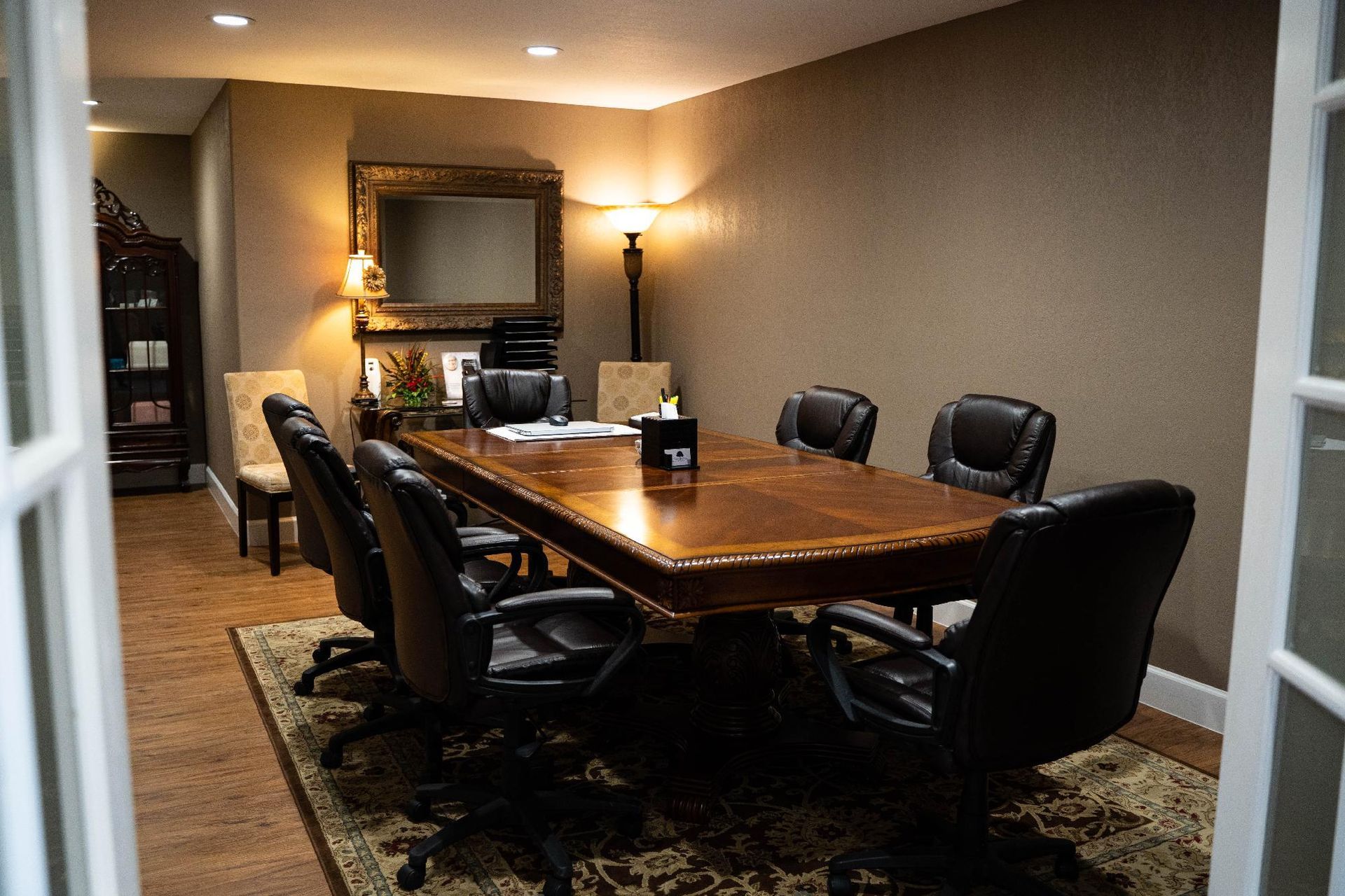 Conference room with a long wooden table, black chairs, and warm wall lighting