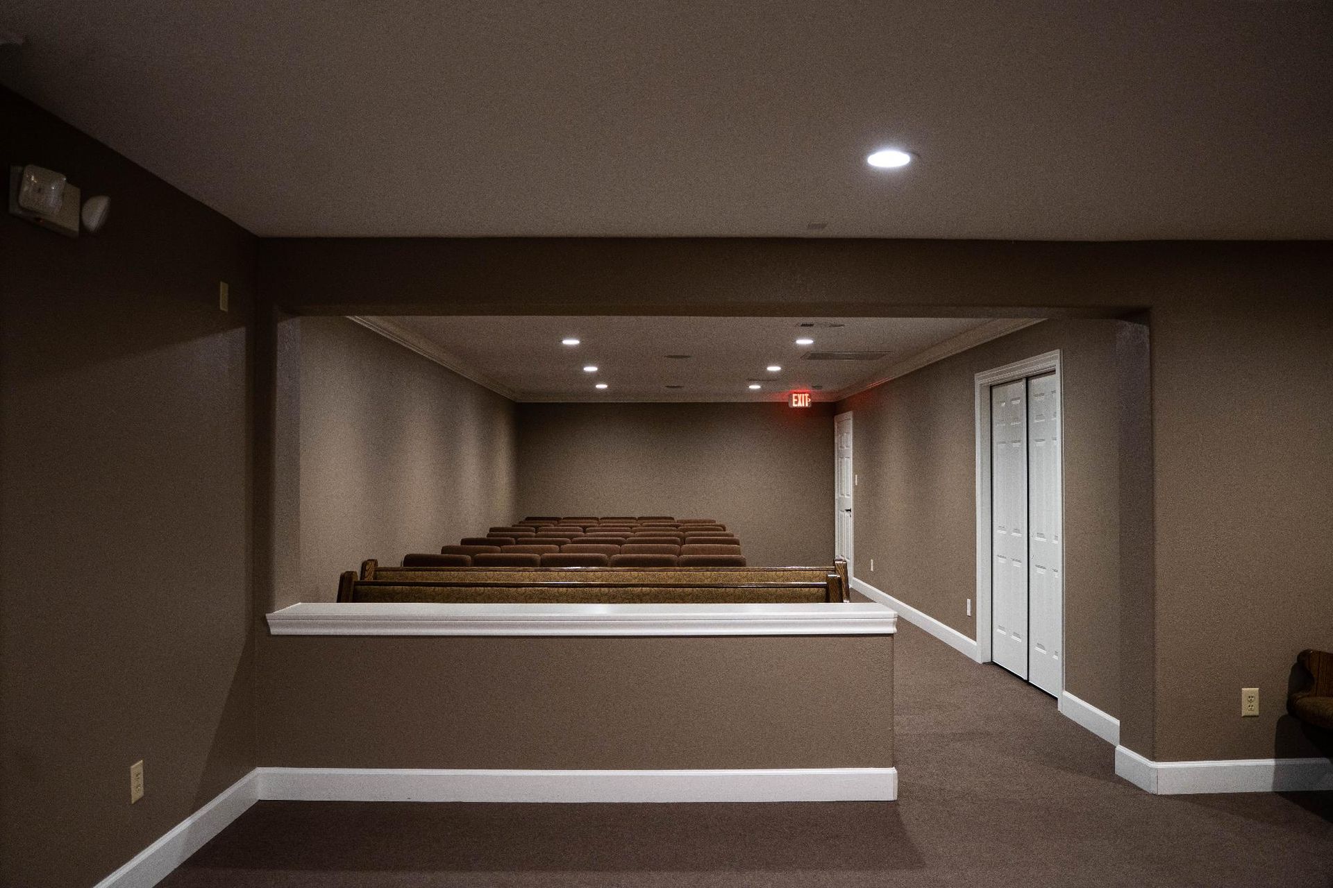 Empty indoor room with stepped seating, beige walls, and recessed ceiling lights