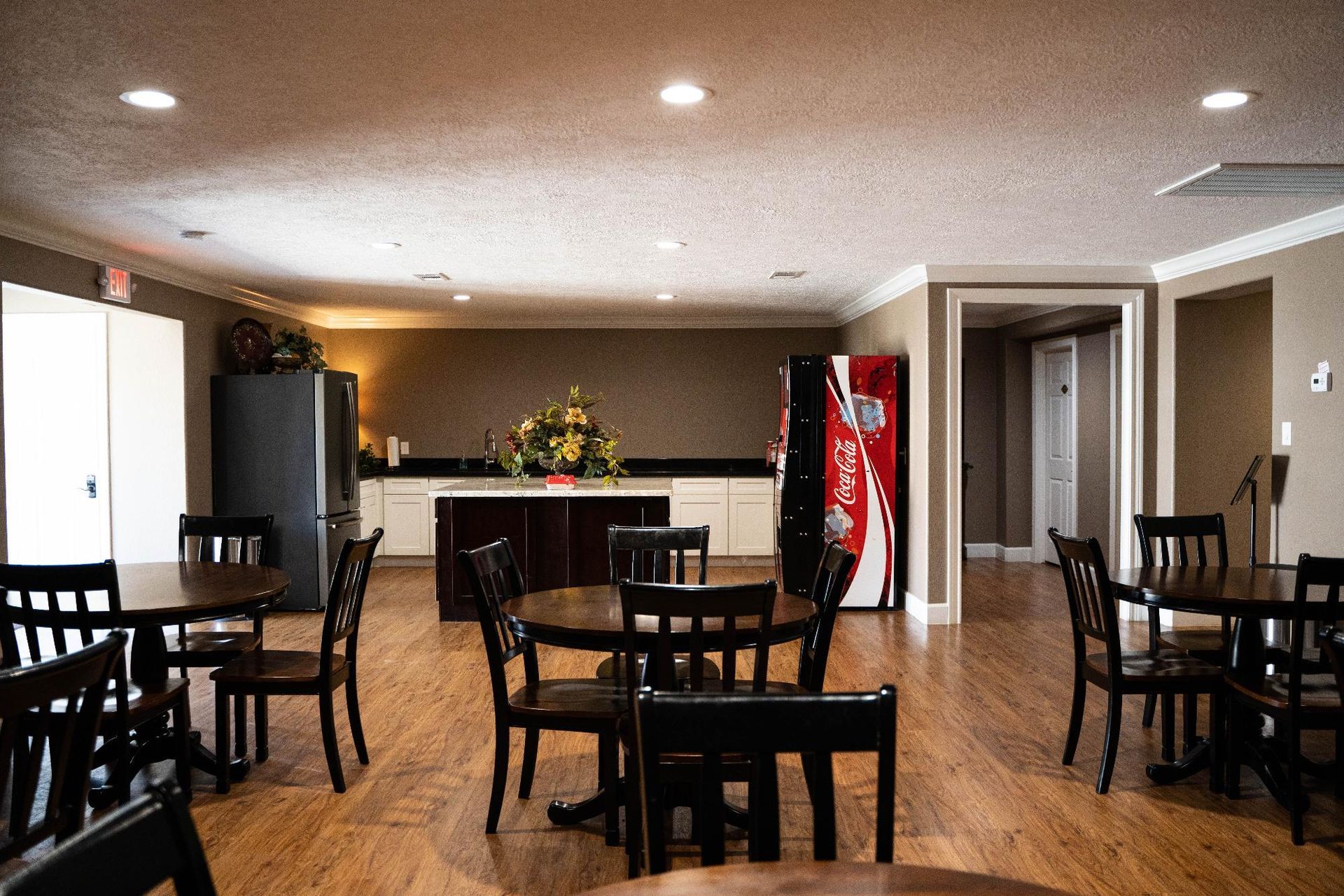 Empty dining room with tables and chairs, a red vending machine, and a counter in the back.