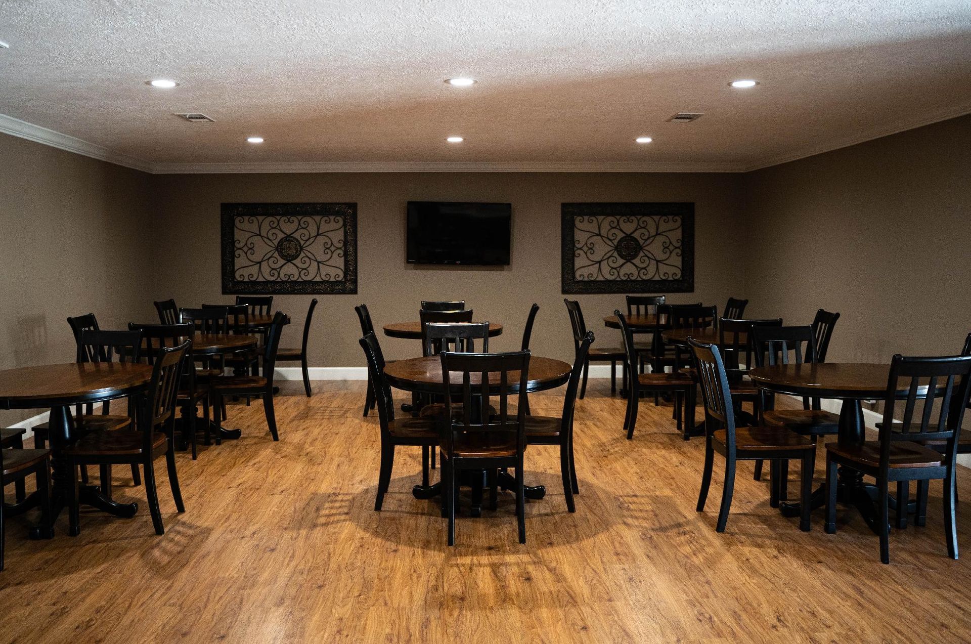 Empty restaurant dining area with dark wood tables and chairs on a hardwood floor