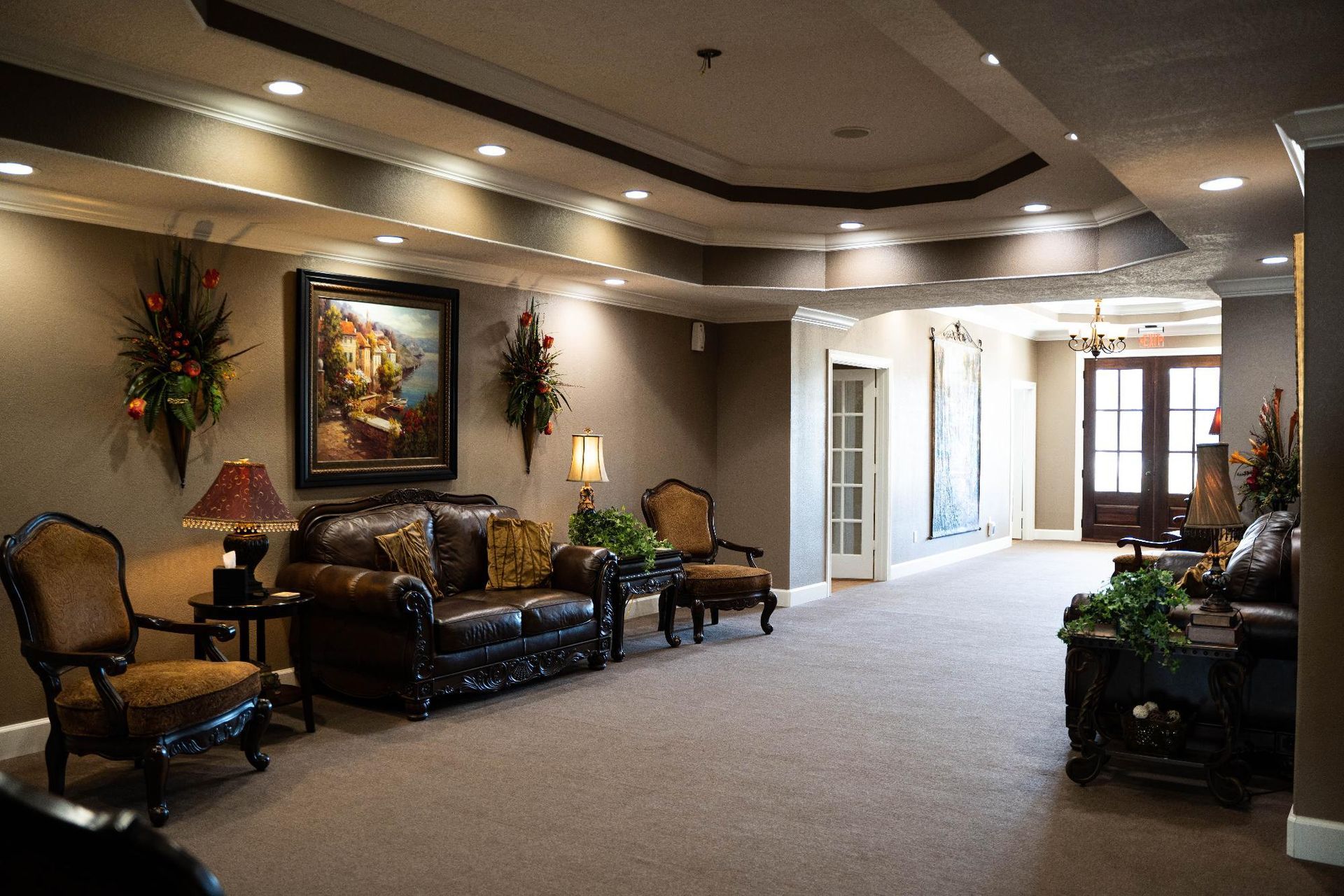 Elegant lobby with leather seating, carpeted floor, artwork, and bright hallway windows