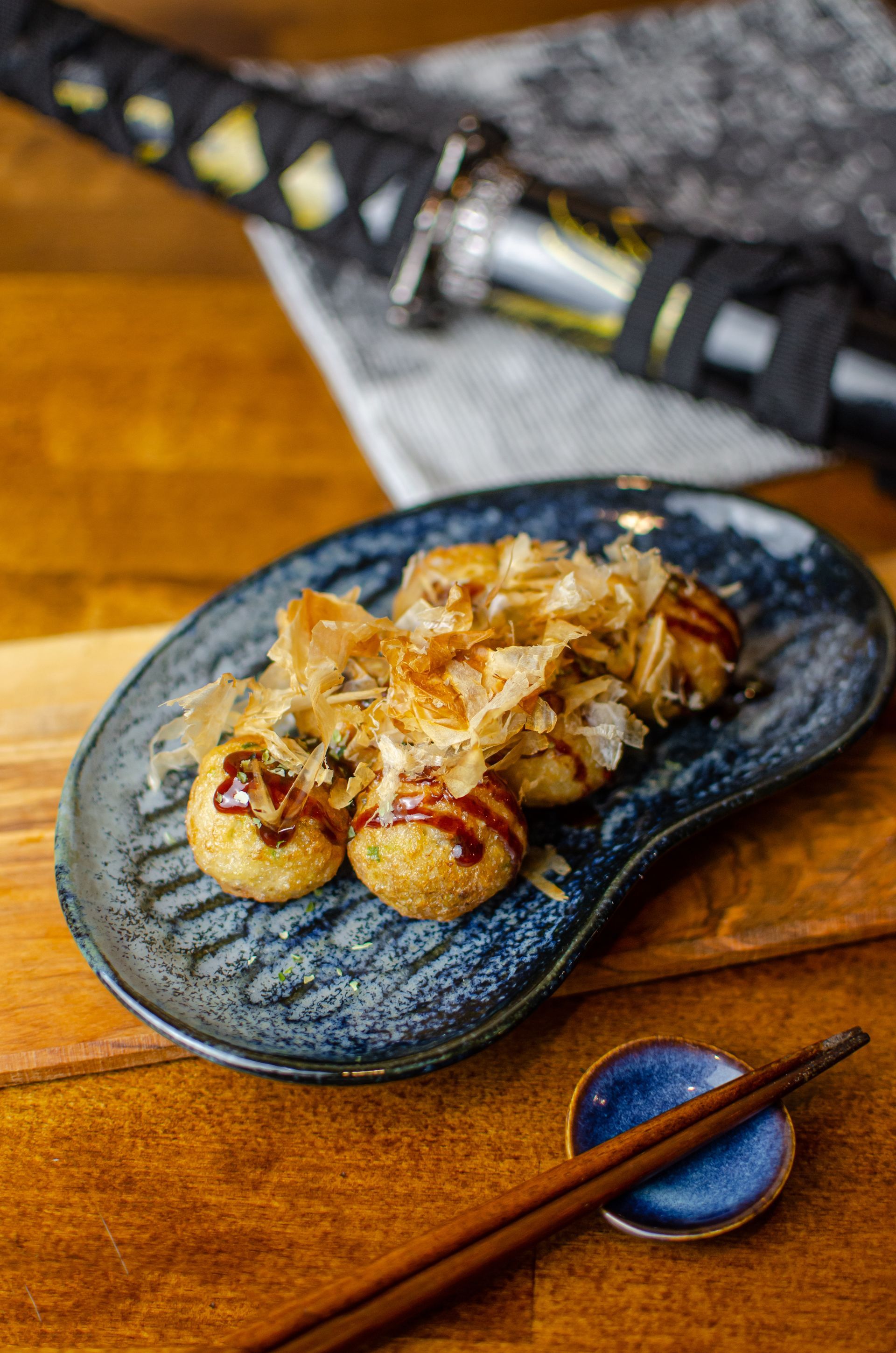 Skewered grilled dumplings on a blue oval plate with chopsticks on a wooden table