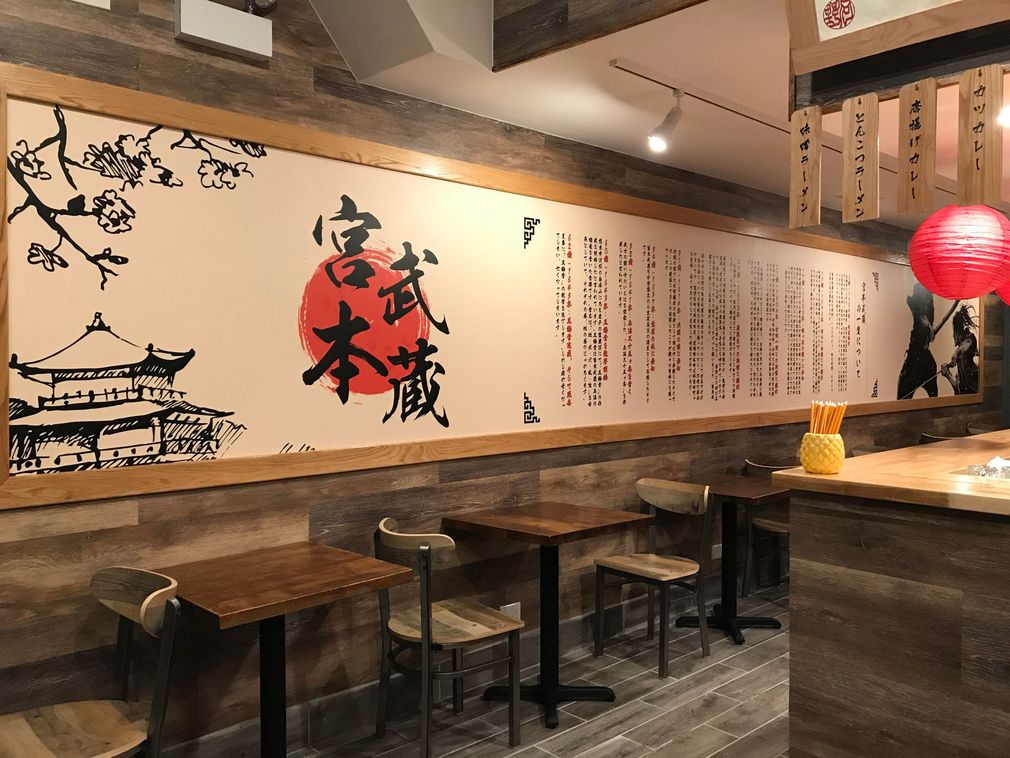 Traditional Japanese restaurant interior with wooden tables, wall art, and a red lantern.