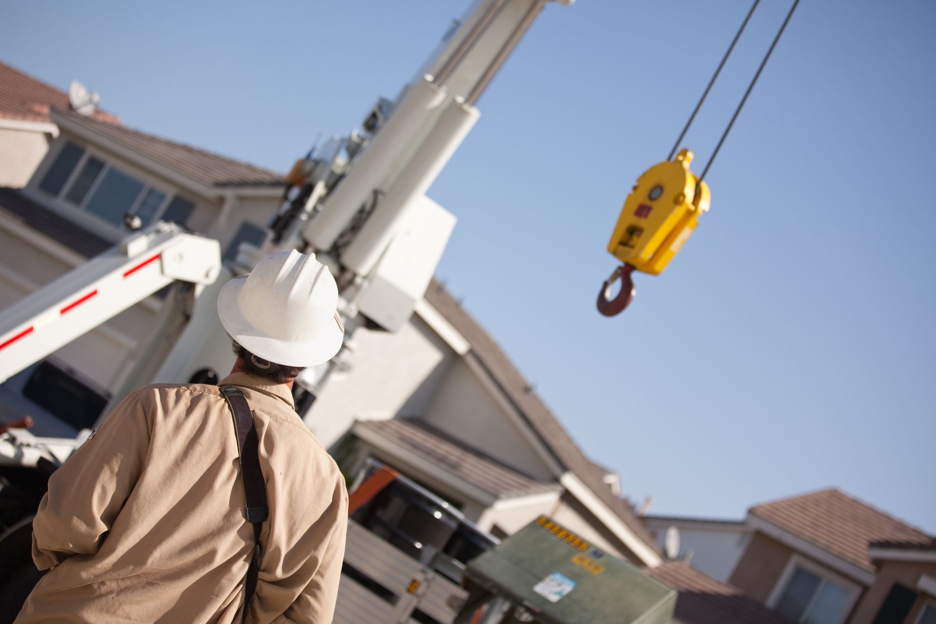 A man wearing a hard hat is standing in front of a crane