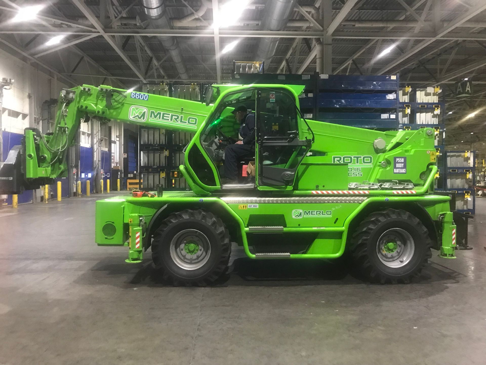 A green crane is parked in a warehouse.