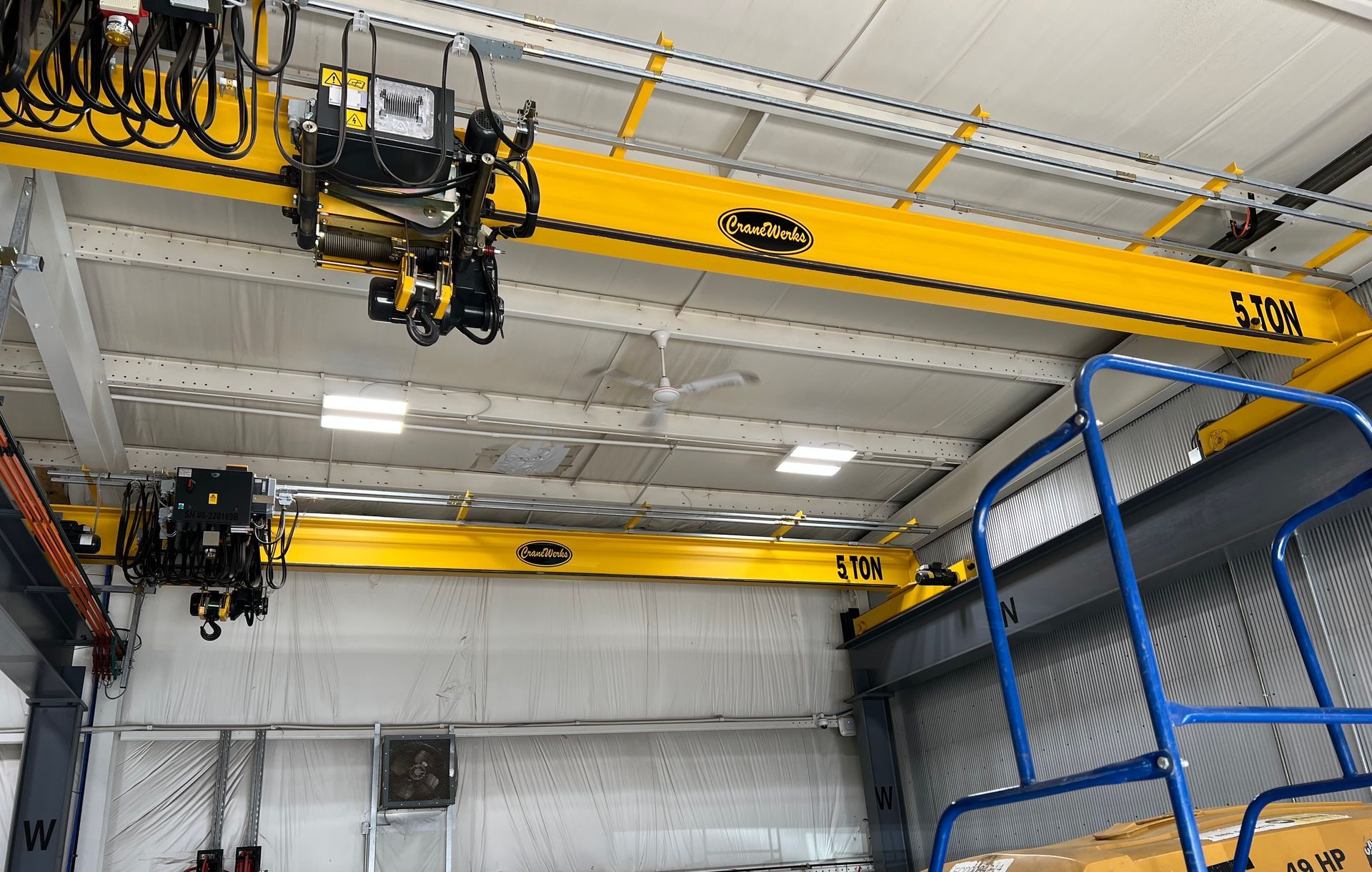 A yellow crane is hanging from the ceiling of a building.