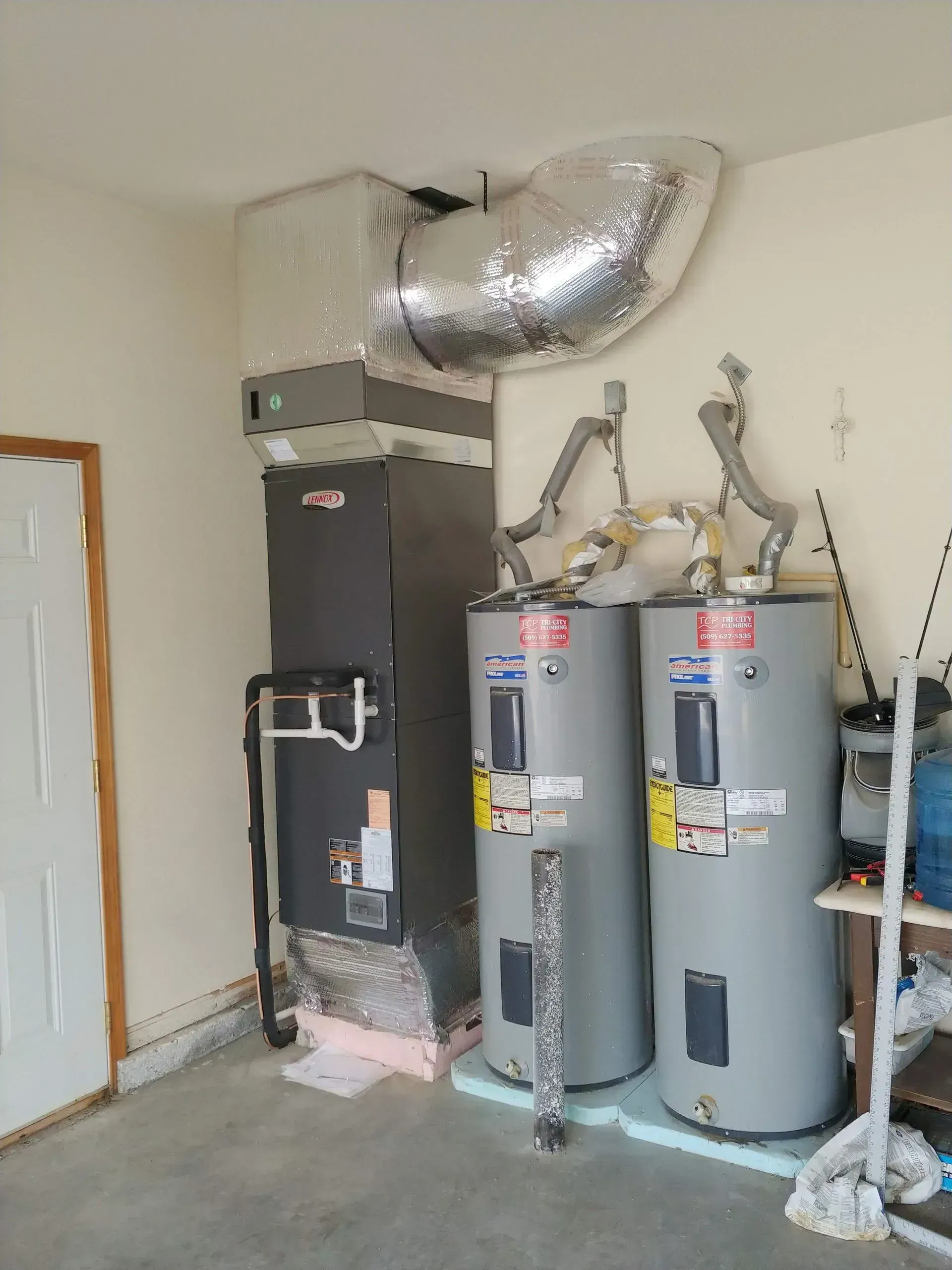 HVAC system and two water heaters in a garage. Ductwork is silver; walls are beige.
