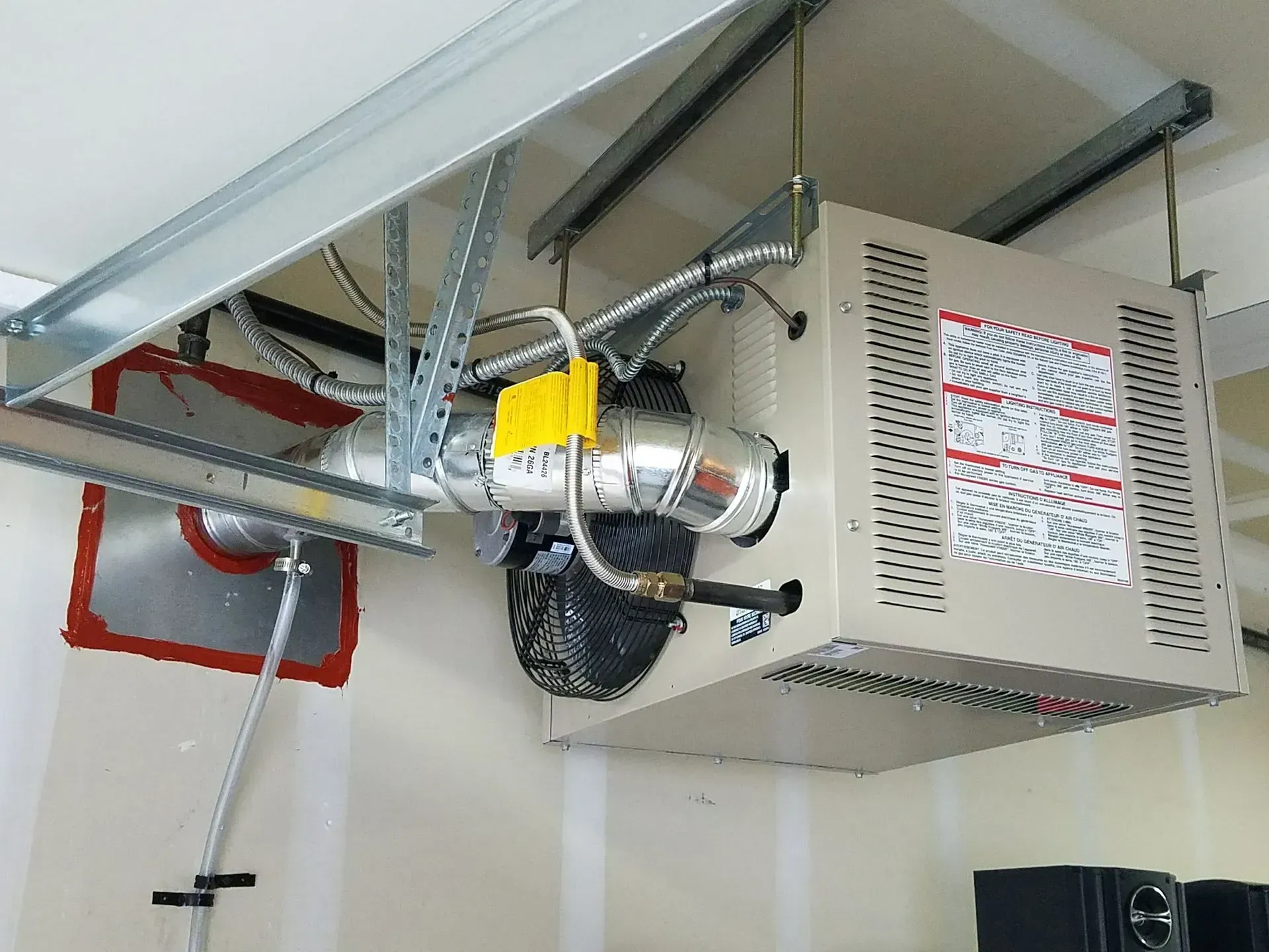 Garage heater unit mounted on ceiling. Beige, metallic, with exhaust tube and air intake.