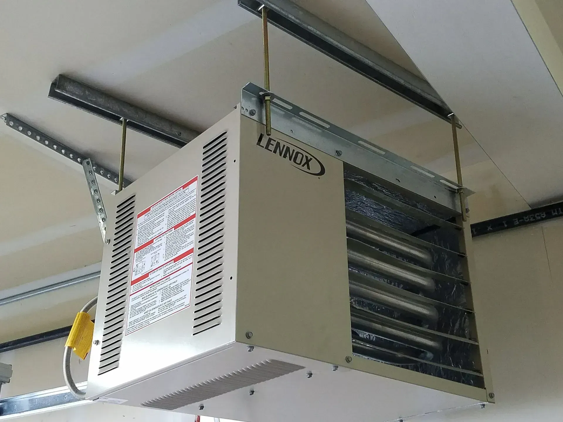 Overhead Lennox garage heater, beige, suspended by metal supports from the ceiling.