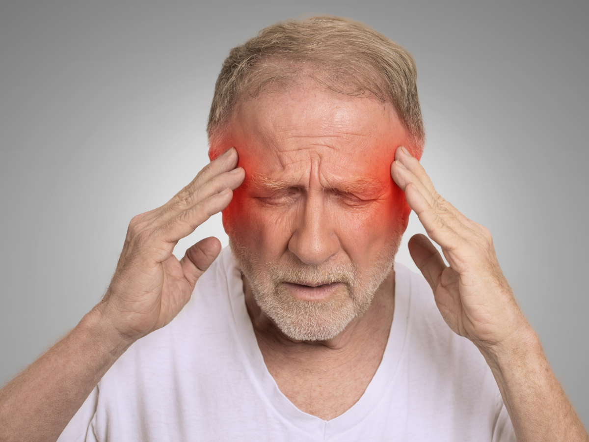 Man holding temples with eyes closed, red highlights over forehead and temples, suggesting a headache