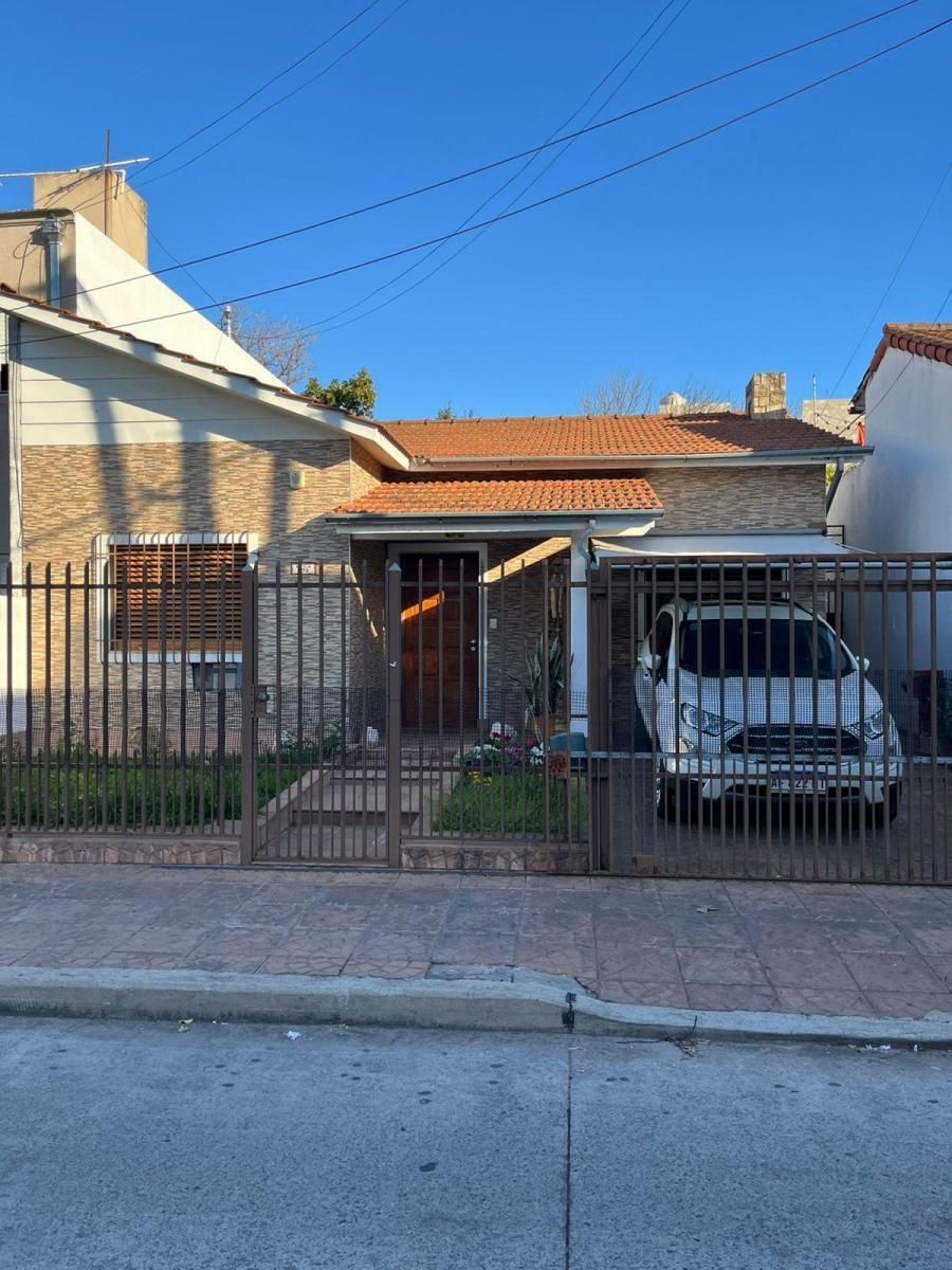 Casa de una sola planta con una valla metálica y una furgoneta blanca aparcada en la entrada.