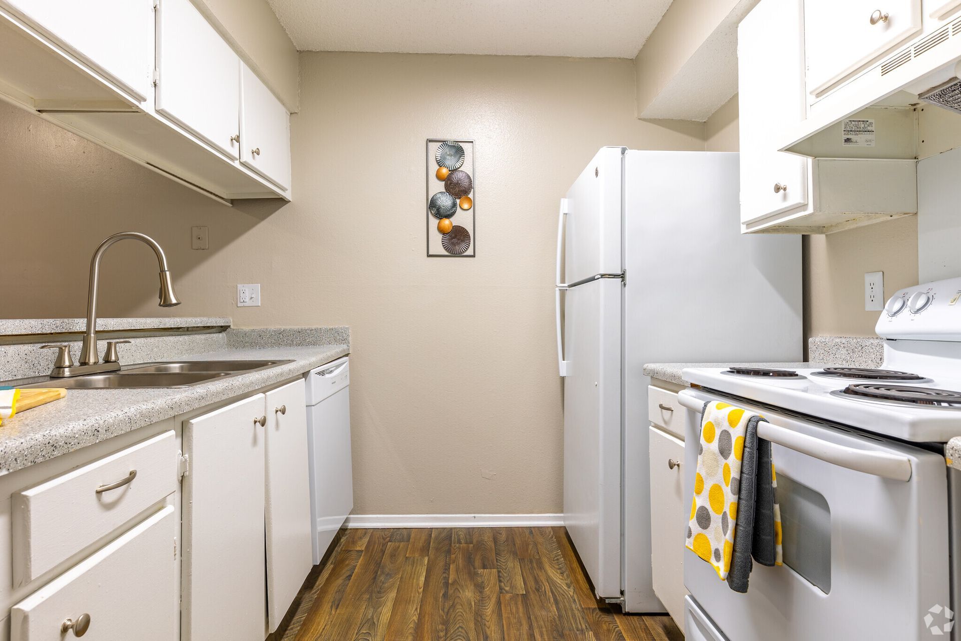 A kitchen with white cabinets , a refrigerator , stove , sink and dishwasher.
