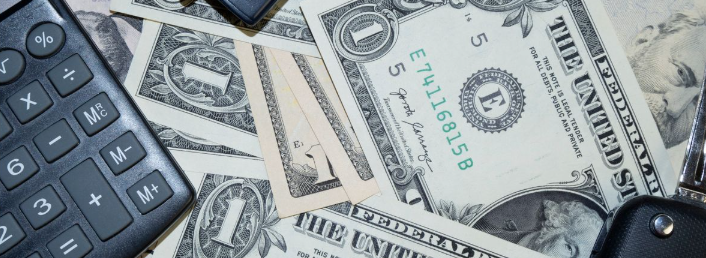 US dollar bills, a calculator and a car key, representing car title loans Covington GA borrowers wei