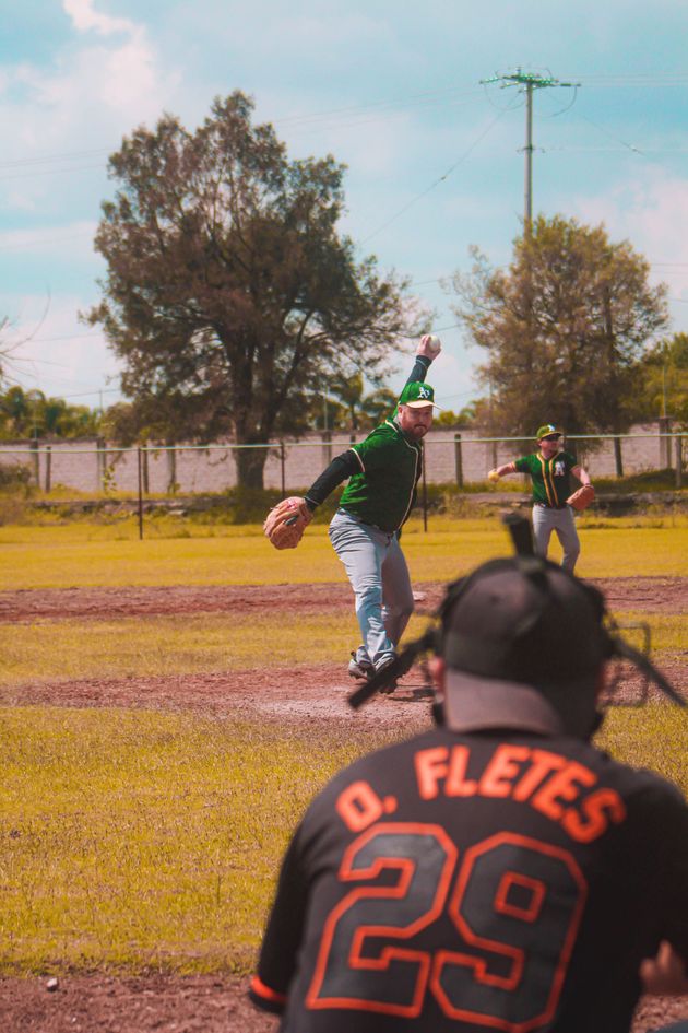 Baseball glove with ball on green grass, with blurred baseballs in the background.