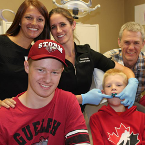 A group of people posing for a picture with one wearing a storm hat