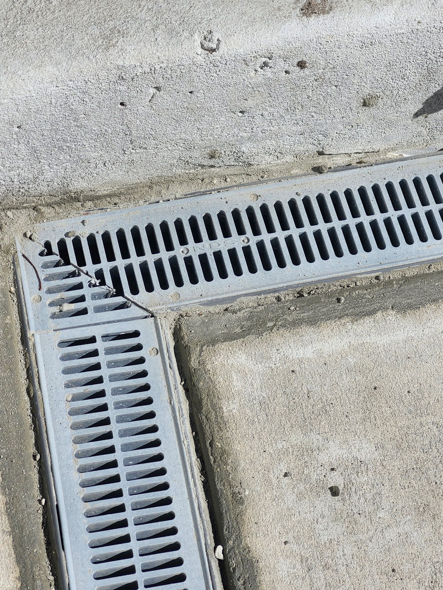 Gray metal drain grates set in concrete.
