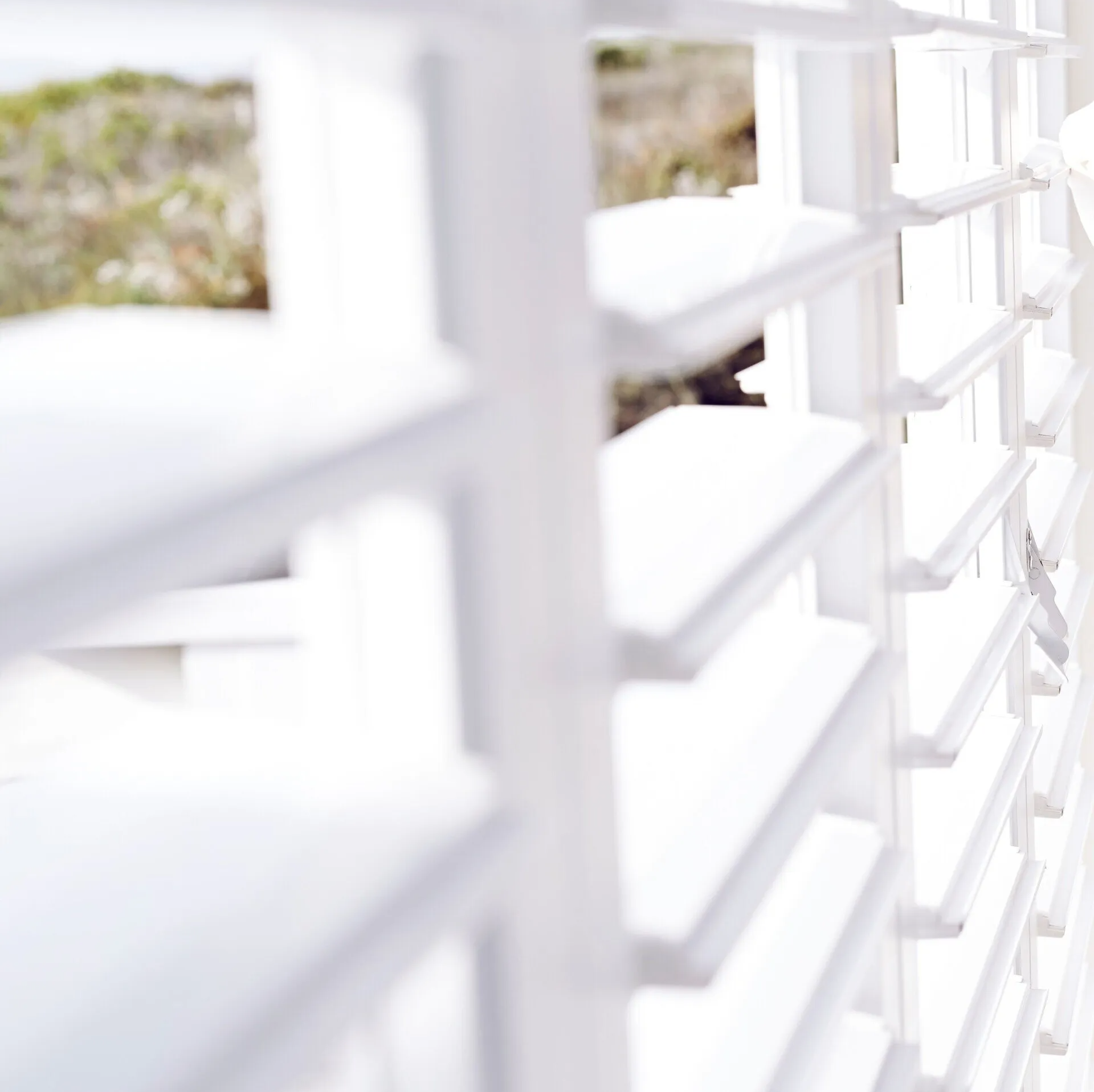 Close up view of white Plantation Shutters open to let in bright sunlight.