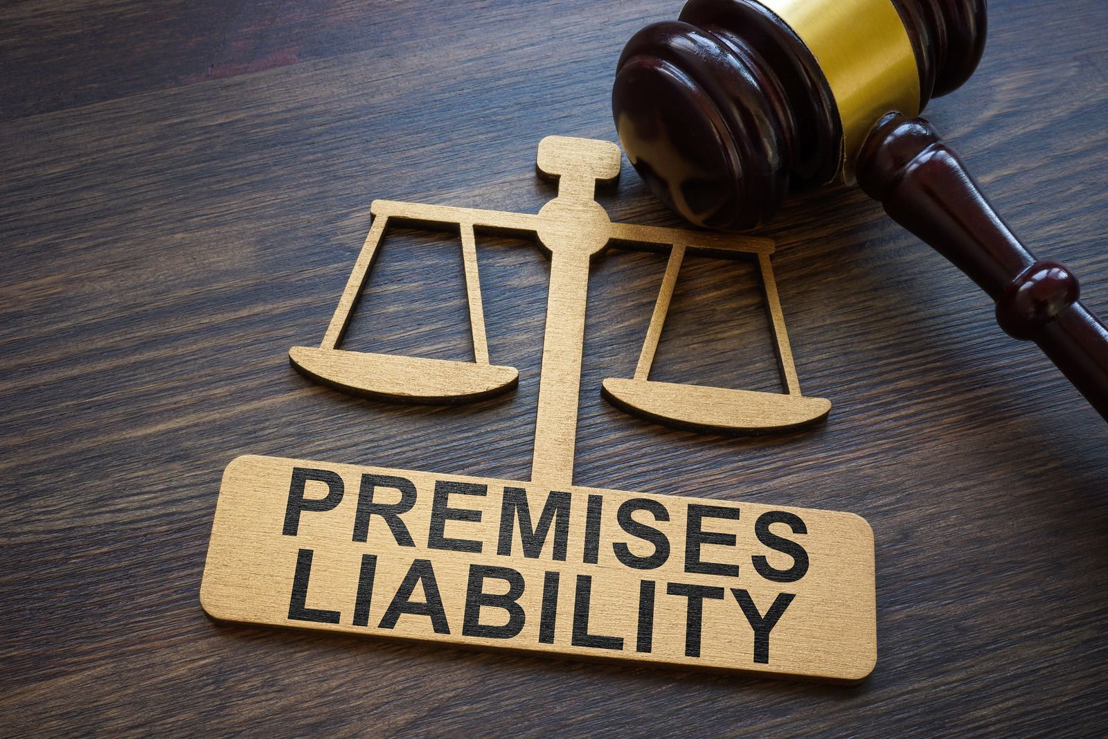A wooden gavel is sitting next to a sign that says premises liability.