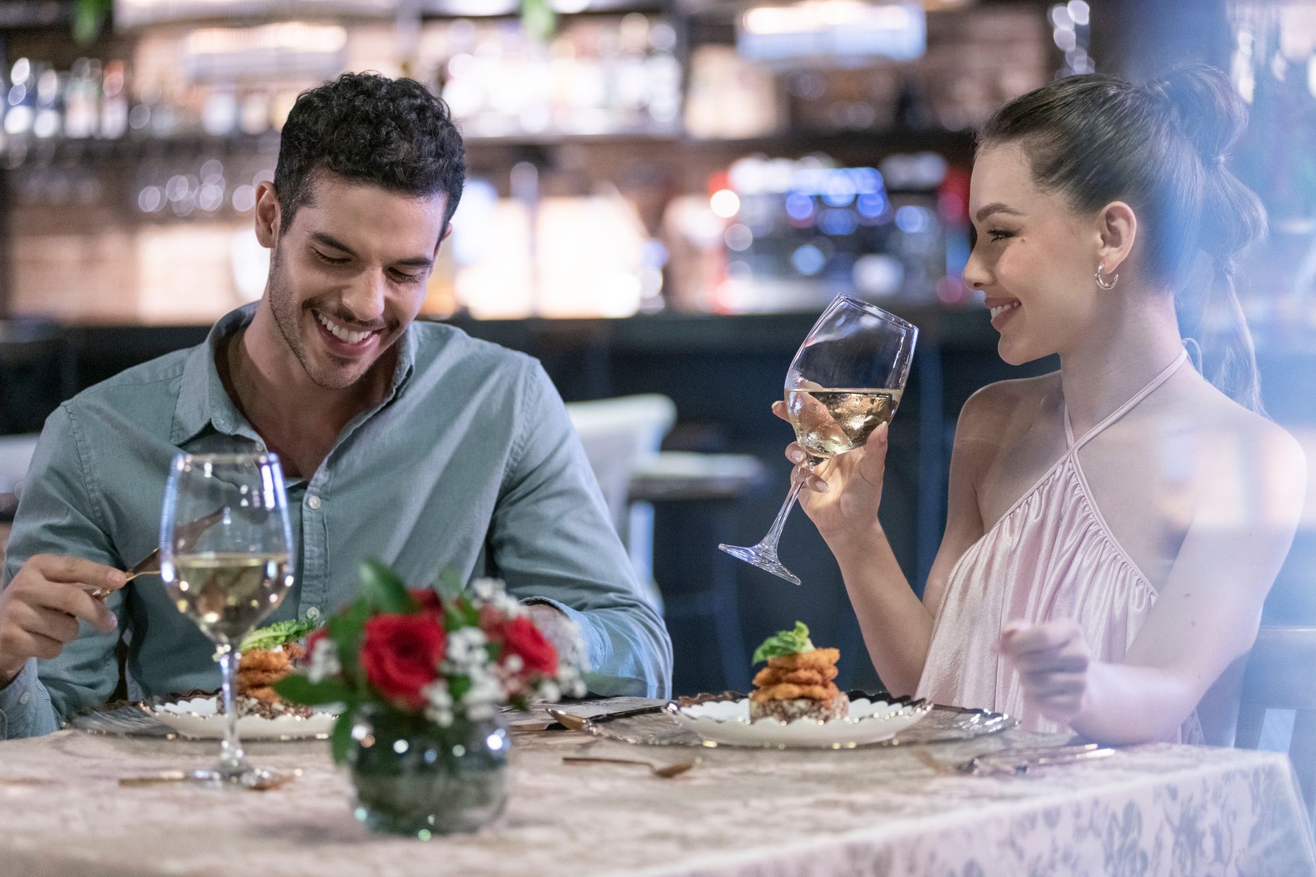 Una mesa con platos, utensilios y un ramo de flores sobre ella.