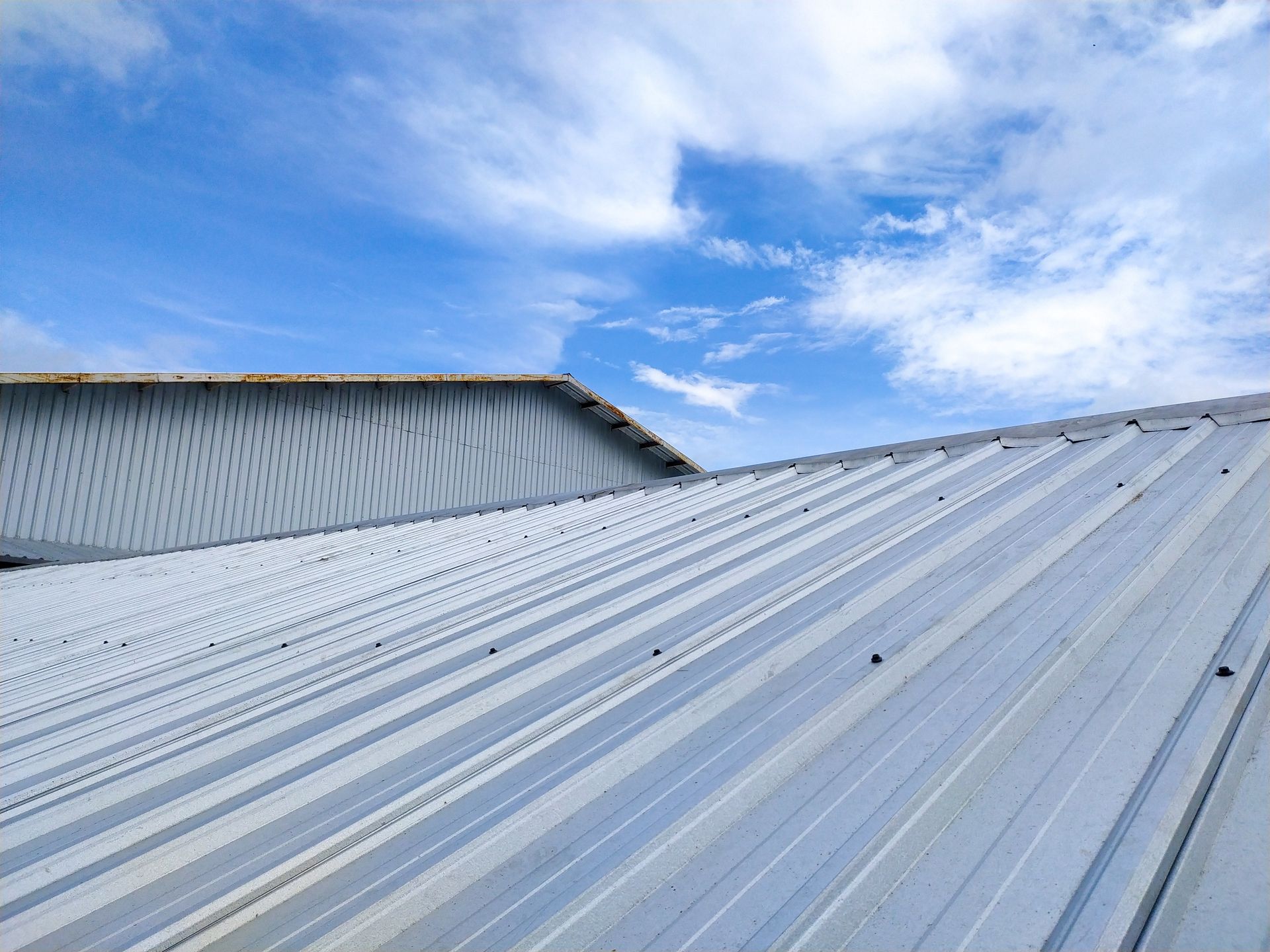 Metal roofs against a bright blue sky with wispy clouds.