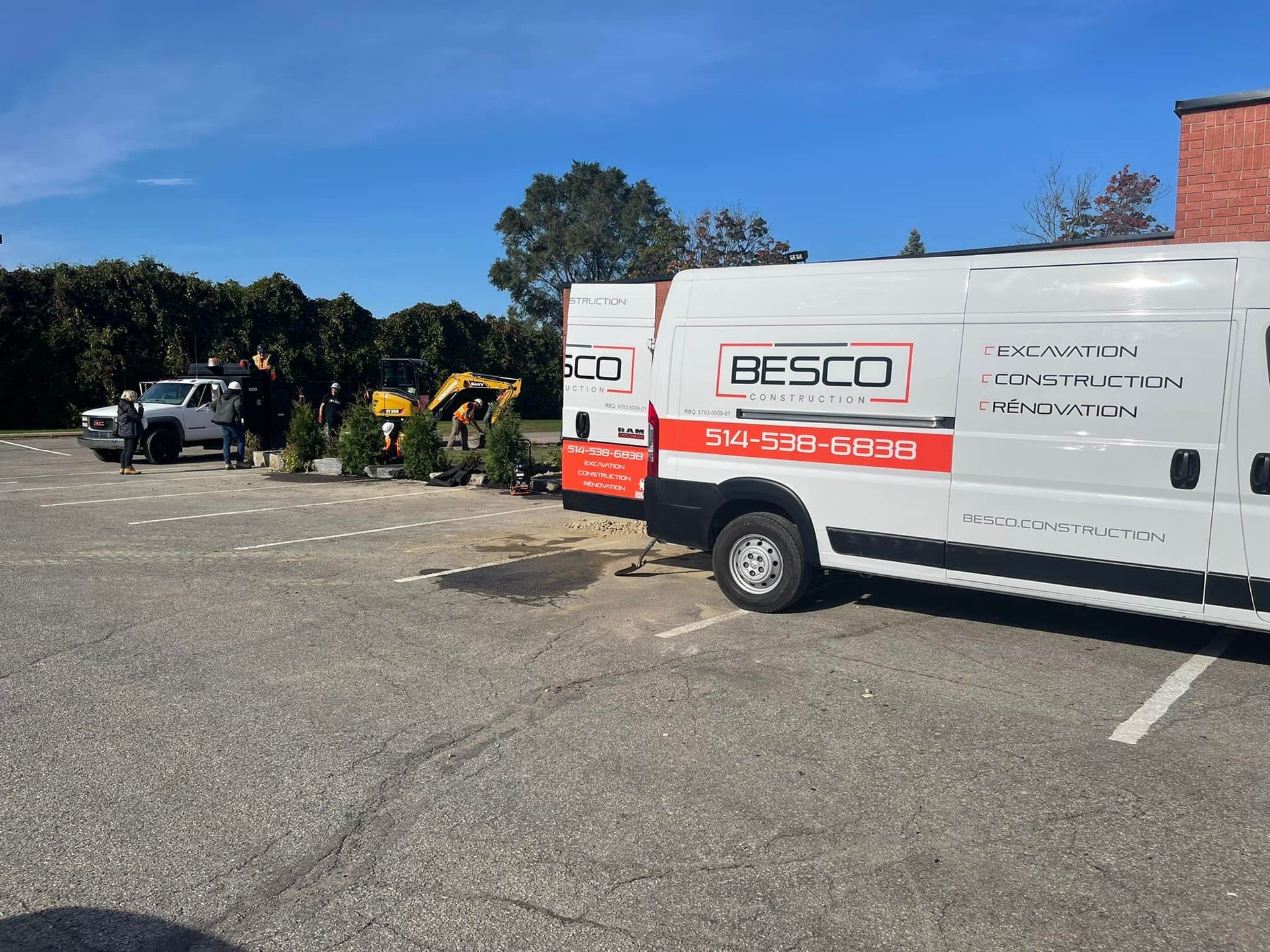 A white RESCO construction van is parked in a paved lot, with workers standing near a yellow excavator in the background.